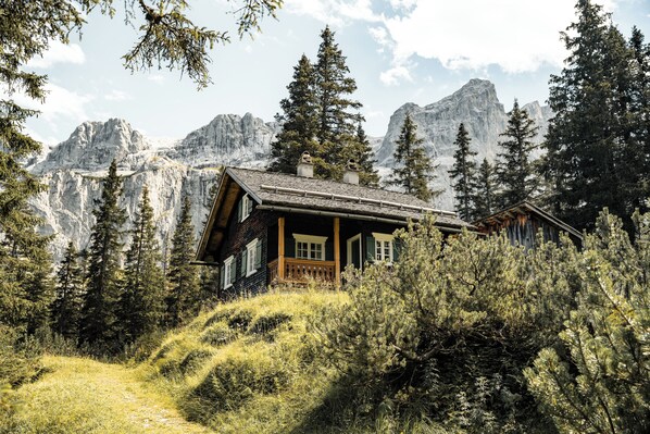A wooden cabin with a balcony, surrounded by trees and mountains. - Amrai Suites (Schruns)