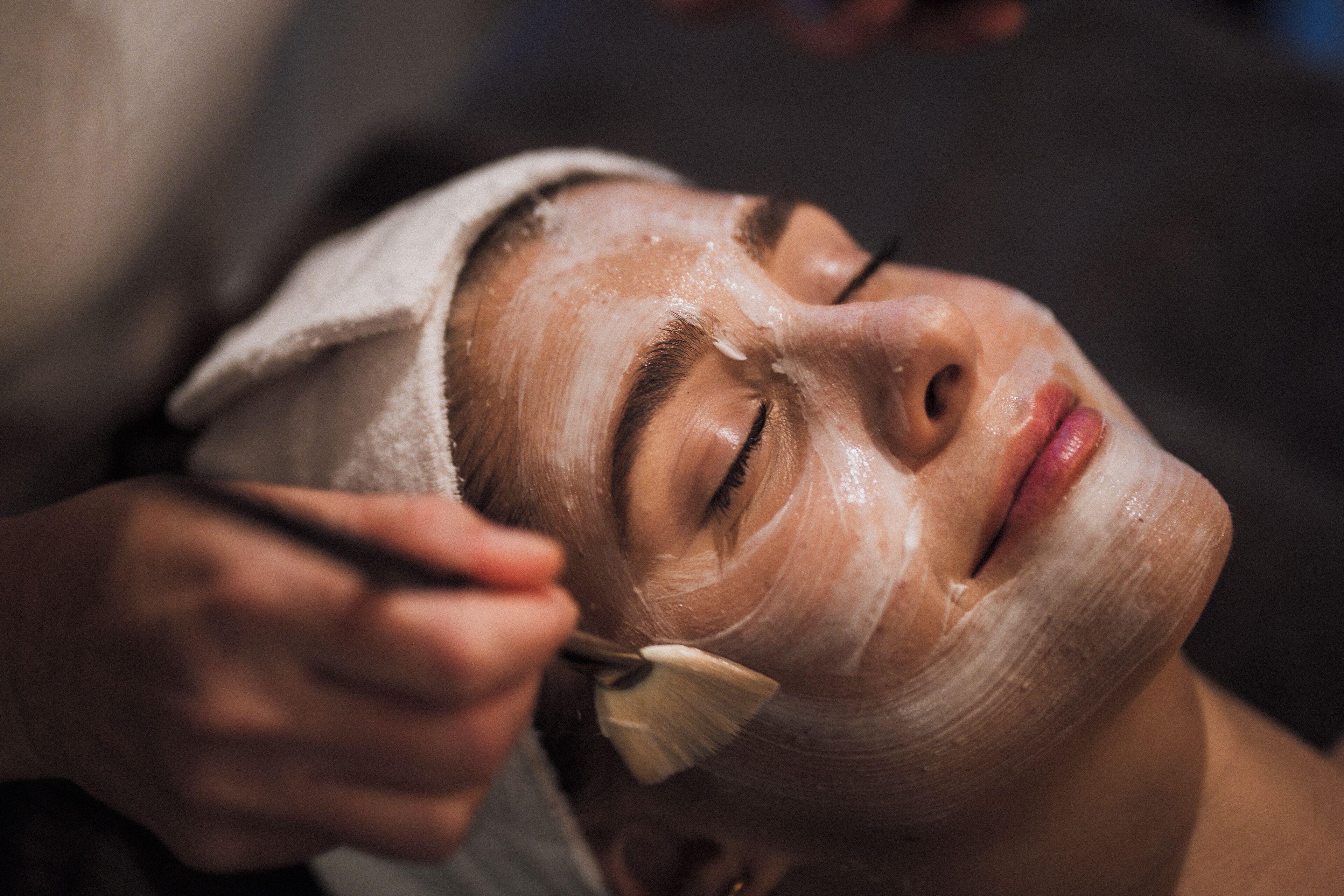 A person receiving a facial treatment with a towel wrapped around their head.