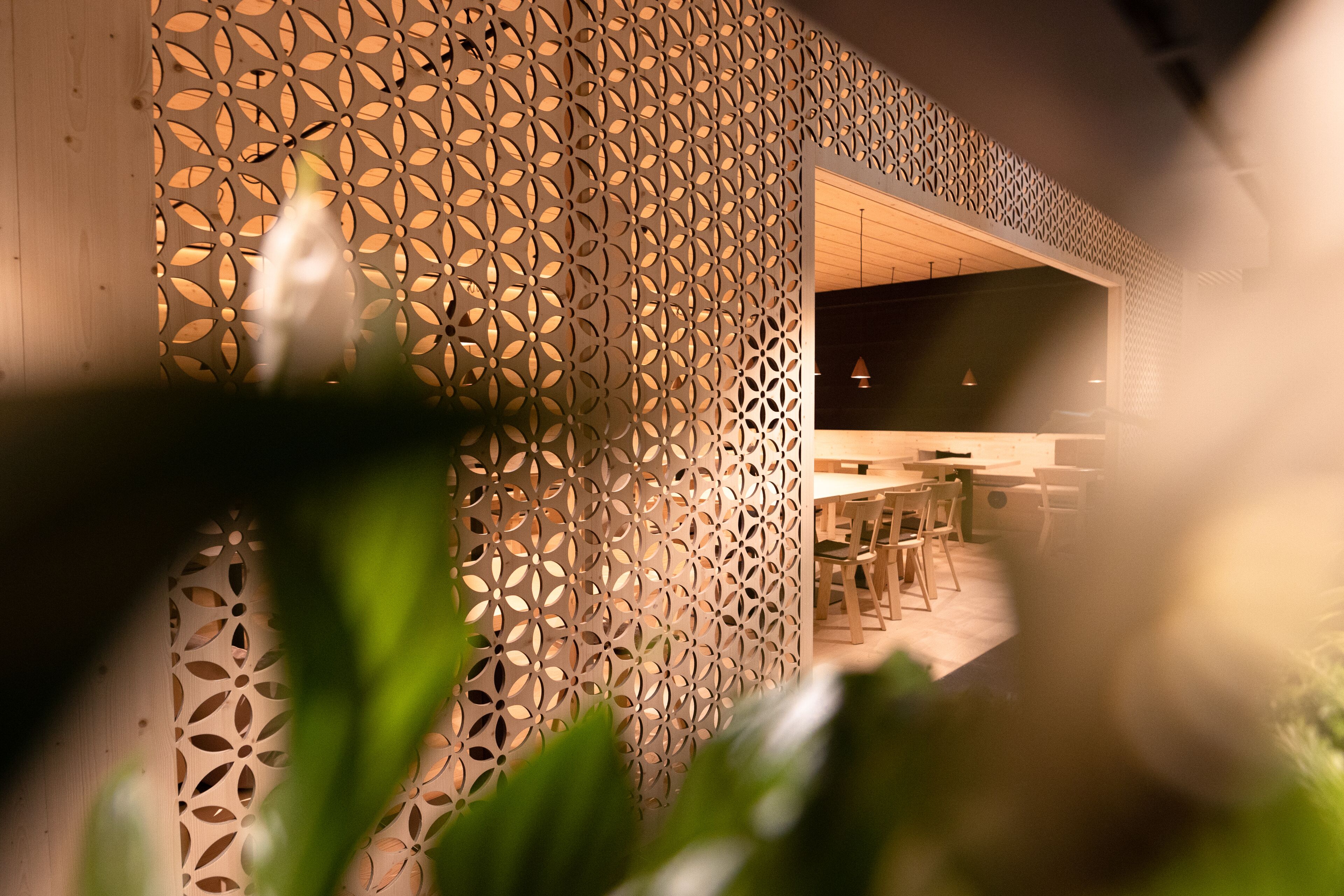 A modern interior with a geometric patterned wall, wooden furniture, and a visible dining area.