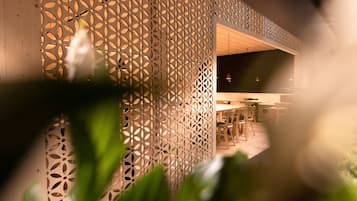 A modern interior with a geometric patterned wall, wooden furniture, and a visible dining area.