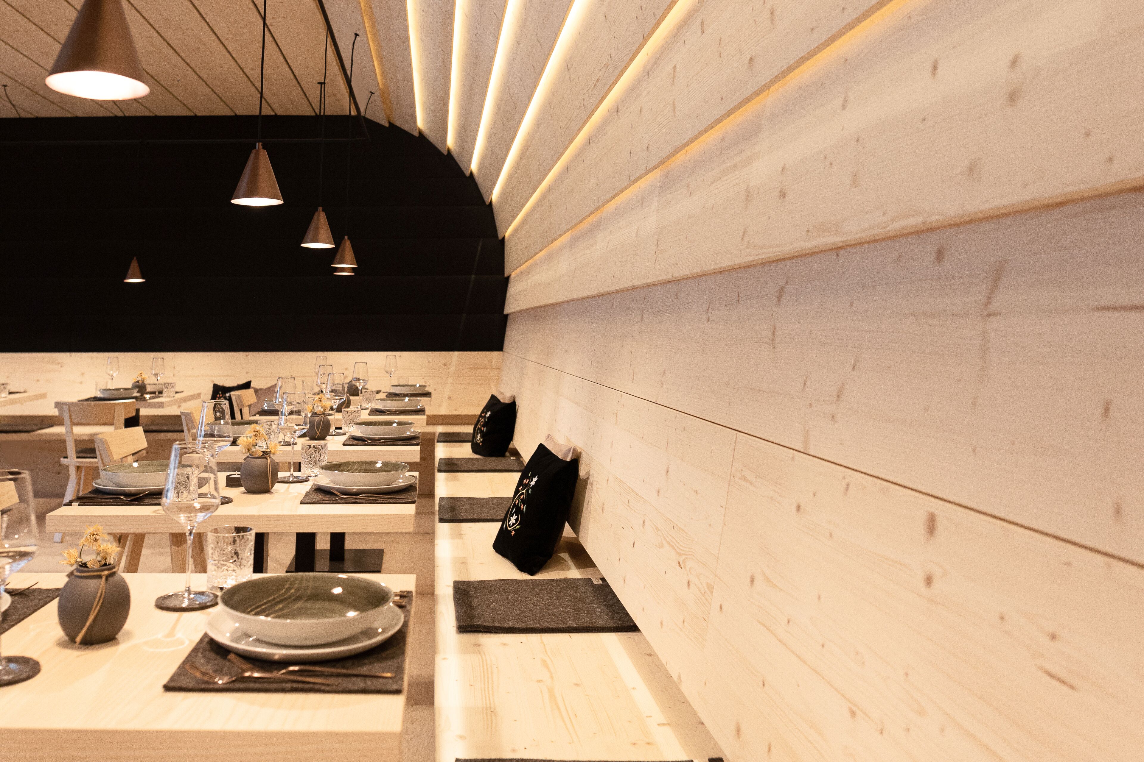 Un restaurante con varias mesas, cada una dispuesta con platos, vasos y cubiertos.