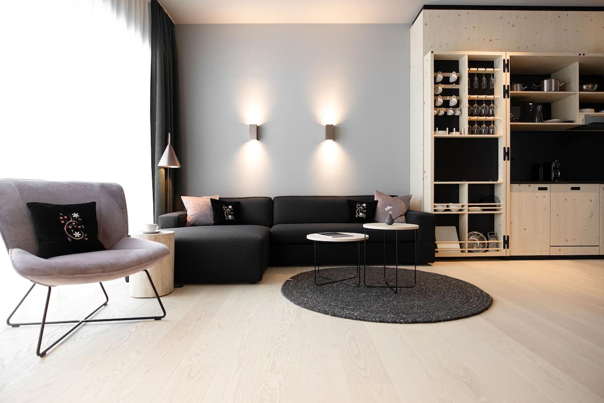 A modern living room with a grey sofa, a round coffee table, and a black armchair.