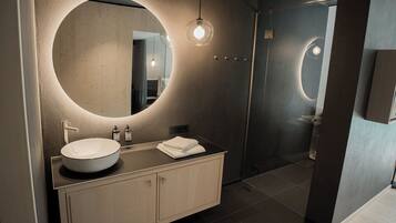 A modern bathroom with a round mirror, a white sink, and a wooden vanity.