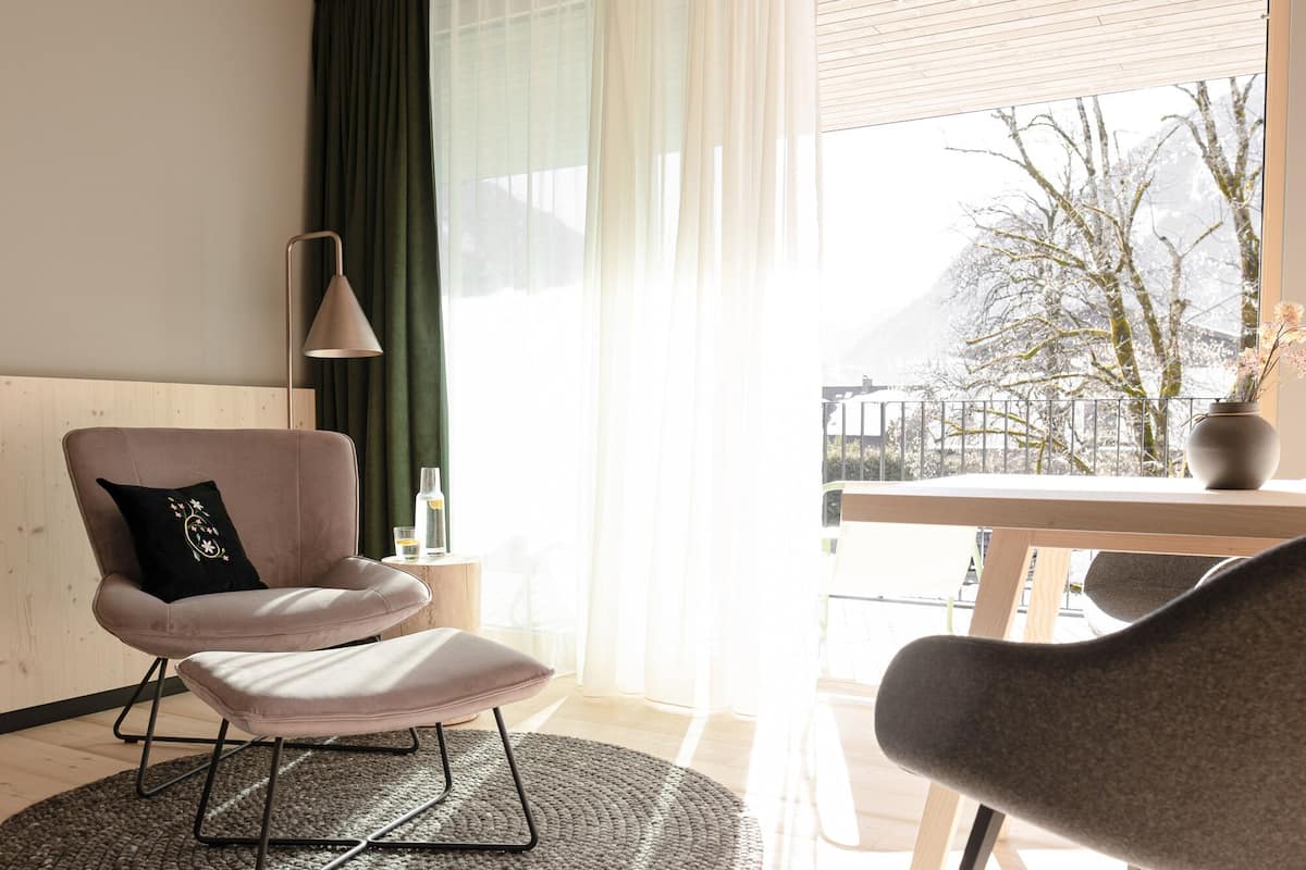 A modern living room with a sofa, a small table with a vase, and a view of a snowy landscape through large windows.