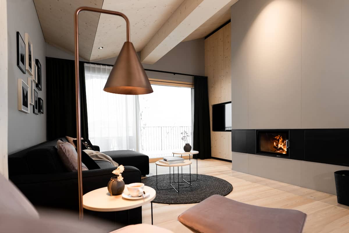 A modern living room with a fireplace, a black sofa, a coffee table, and a round rug.