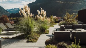 A patio area with outdoor seating and a view of mountains. - Amrai Suites (Schruns)