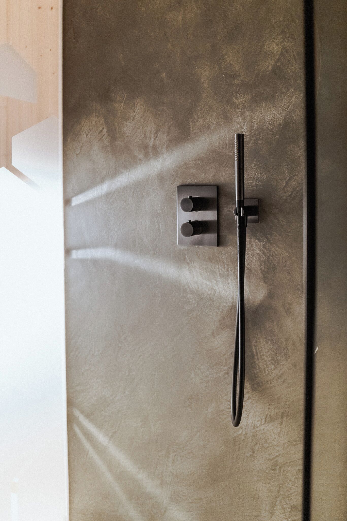 Eine Dusche mit Handbrause und Bedienfeld an der Wand.