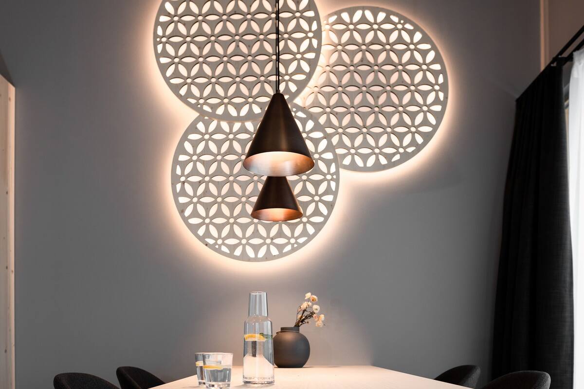 A modern dining area with a white table, black chairs, and a pendant light.