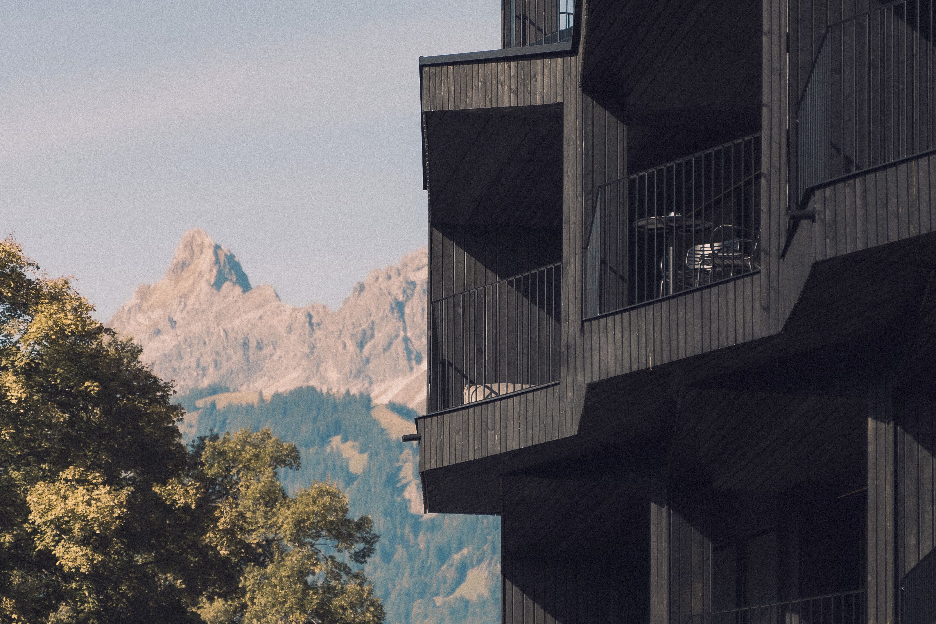 A modern building with balconies overlooking a mountainous landscape.