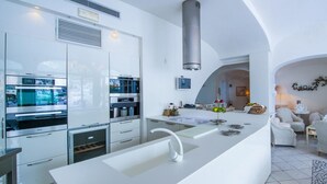 Eine moderne Küche mit weißen Schränken, einer Edelstahl-Dunstabzugshaube und einer zentralen Kochinsel mit Spüle.