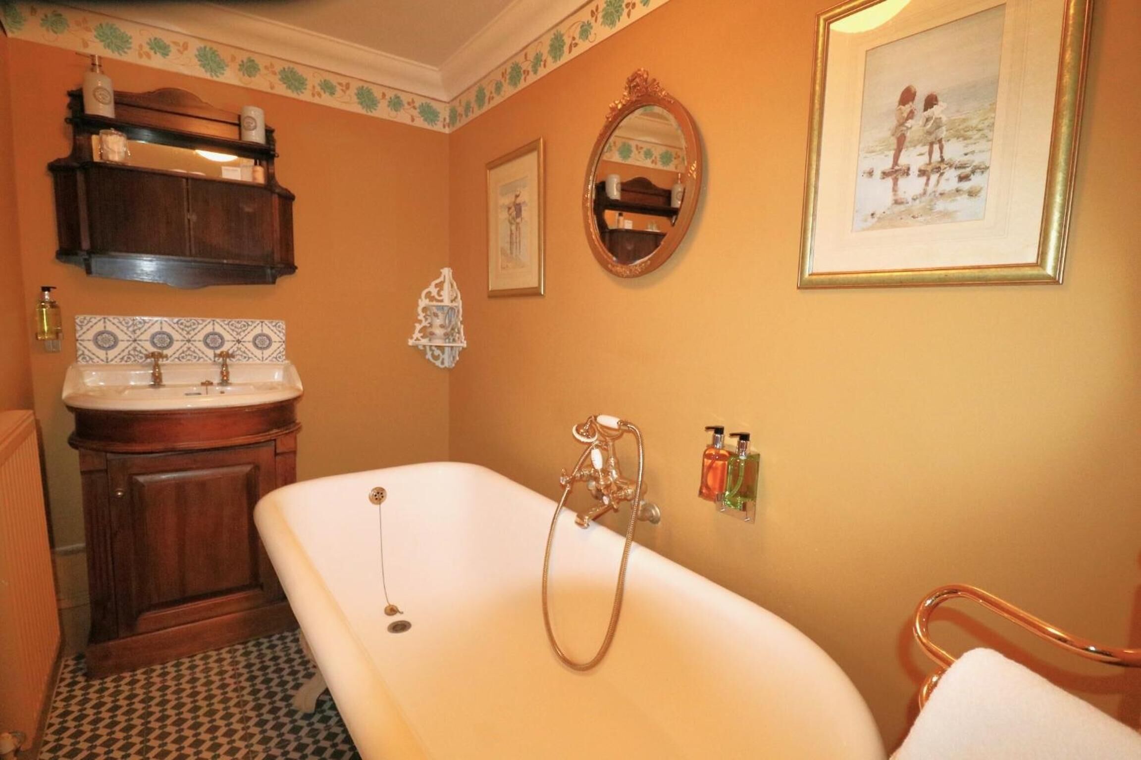 Un baño con una bañera independiente, un tocador de madera con un espejo y un revoque de azulejos.