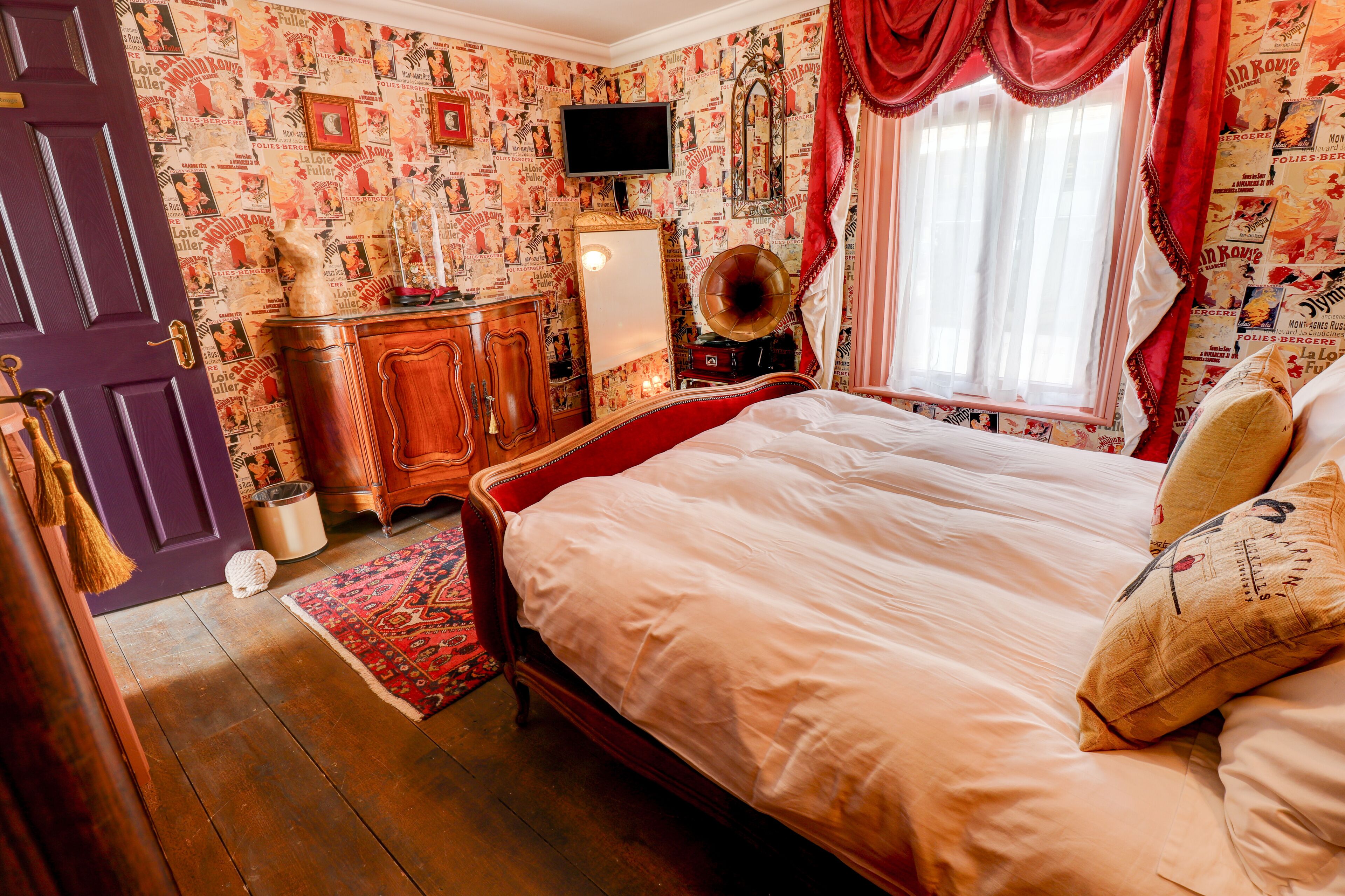 Un dormitorio con una cama de madera, un aparador, un espejo y un televisor en la pared.