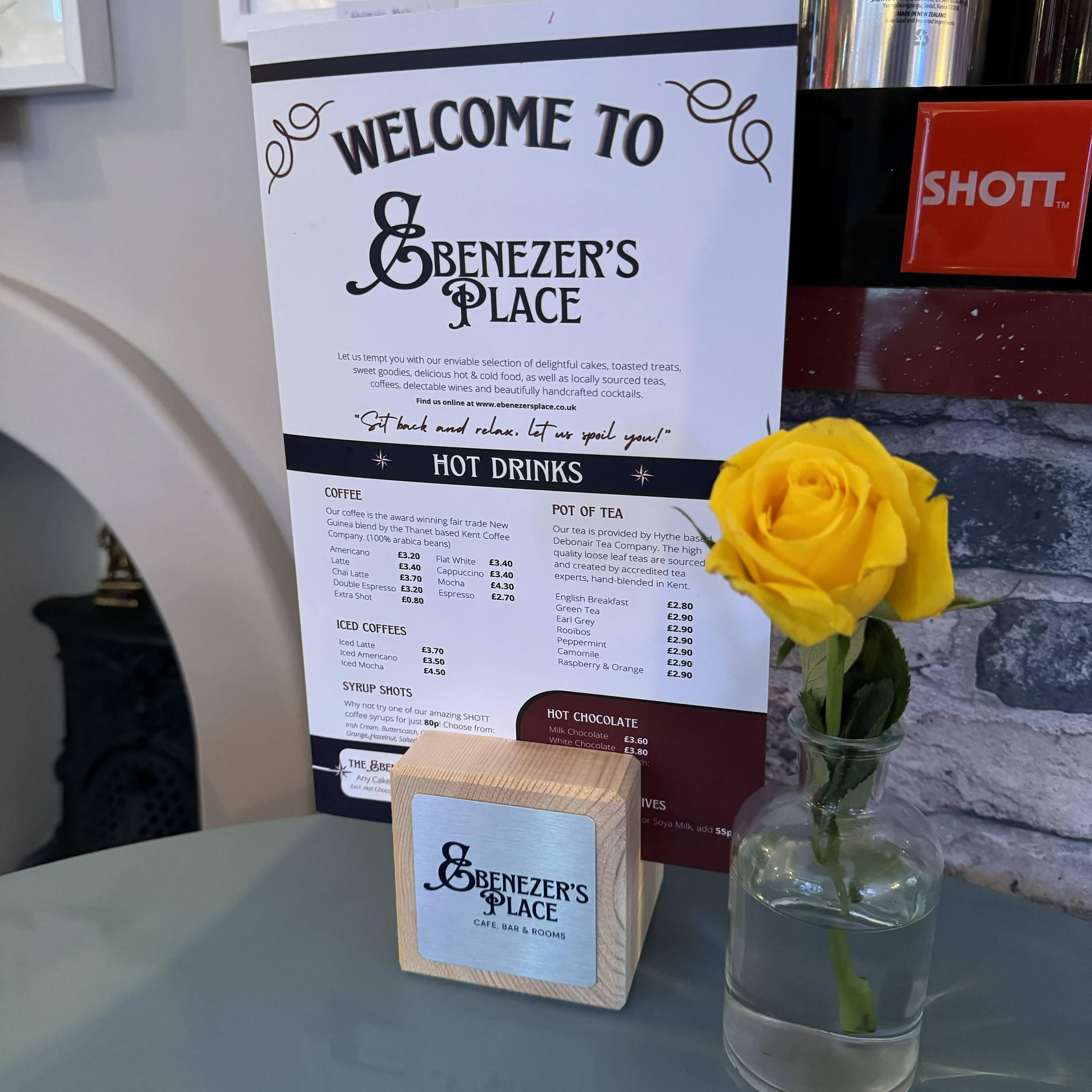 A menu board at Benezzer's Place with sections for hot drinks, iced coffees, and syrups.