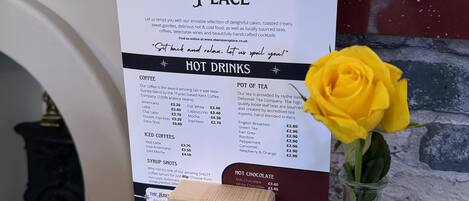 A menu board at Benezzer's Place with sections for hot drinks, iced coffees, and syrups.