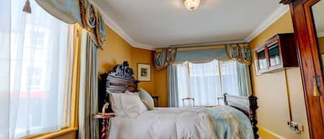 A classic bedroom with a four-poster bed, ornate curtains, and a chandelier.