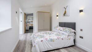 A bedroom with a bed, a wardrobe, a bathroom, and a hallway. - 2 bedroom accommodation in Santon Downham (Santon Downham)