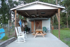 A covered outdoor area with a picnic table and a rocking chair. - House with fenced  yard, pets welcome, one level,  Supply, NC (Supply)
