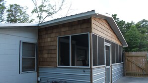 A single-story house with a covered porch, a sliding metal door, and a wooden exterior. - House with fenced  yard, pets welcome, one level,  Supply, NC (Supply)