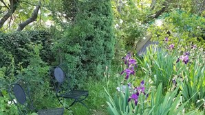 Un giardino con una sedia in metallo e fiori viola.