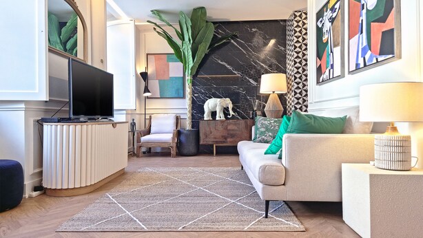 Una sala de estar moderna con un sofá, una mesa de centro, un televisor y una planta grande.