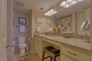 A bathroom with a toilet, sink, vanity, and a mirror.