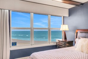 Et hotelværelse med et stort vindue der udover havet.