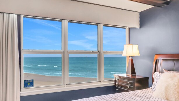 A hotel room with a large window offering a view of the beach and ocean. - Direct Beach Front, High End Vacation,Snow Bird Special WINTER 2027 (St. Augustine)