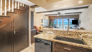 A modern kitchen with granite countertops, a dishwasher, and a large window overlooking a balcony. - Direct Beach Front, High End Vacation,Snow Bird Special WINTER 2027 (St. Augustine)