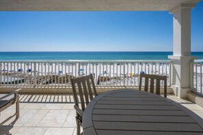 A covered outdoor seating area with a view of the beach and ocean.