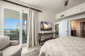 A hotel room with a balcony, a bed, a TV, and a desk.