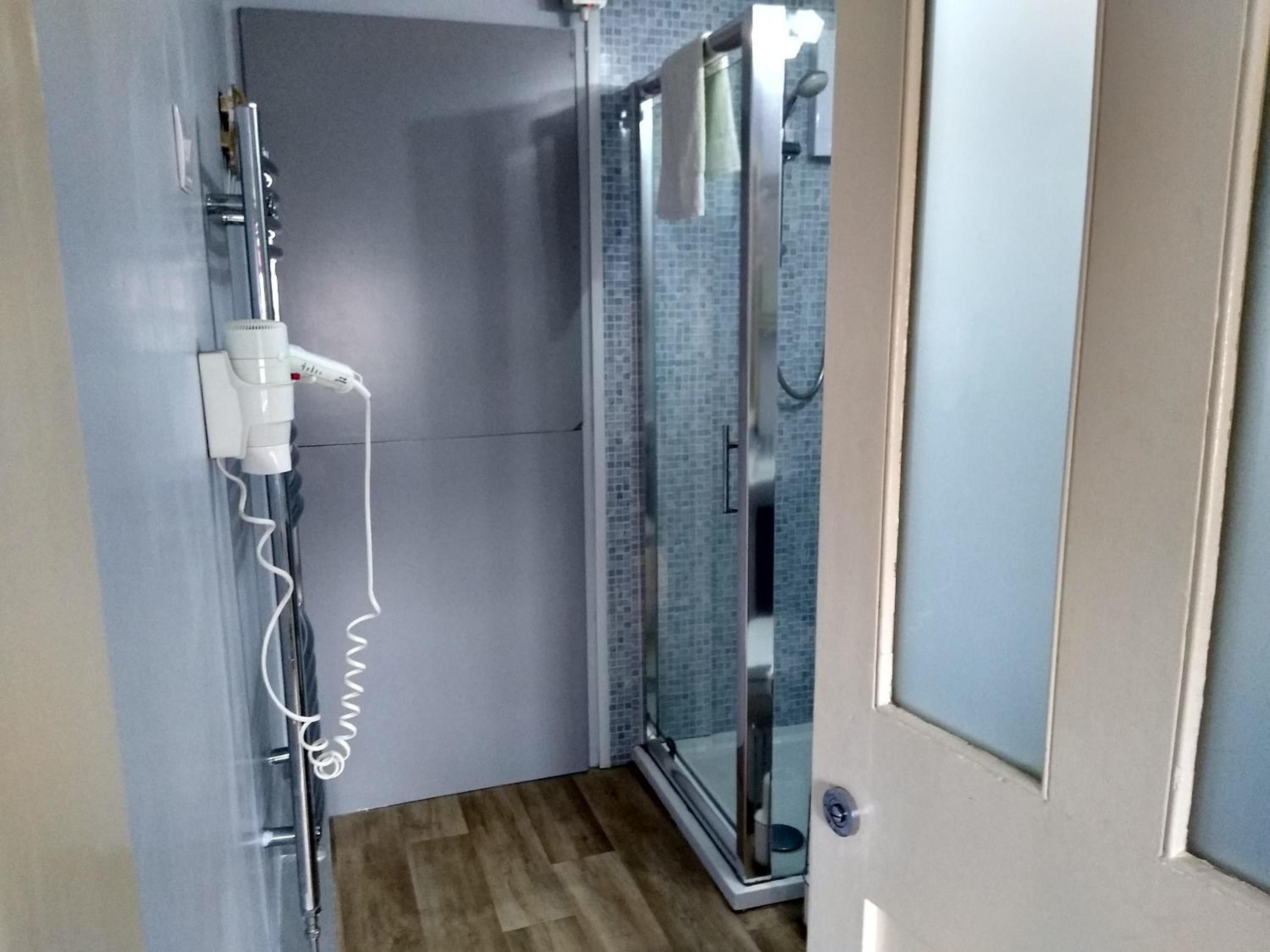 Une salle de bain avec une douche, un porte-serviettes et une prise de courant.