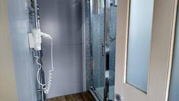 Une salle de bain avec une douche, un porte-serviettes et une prise de courant.