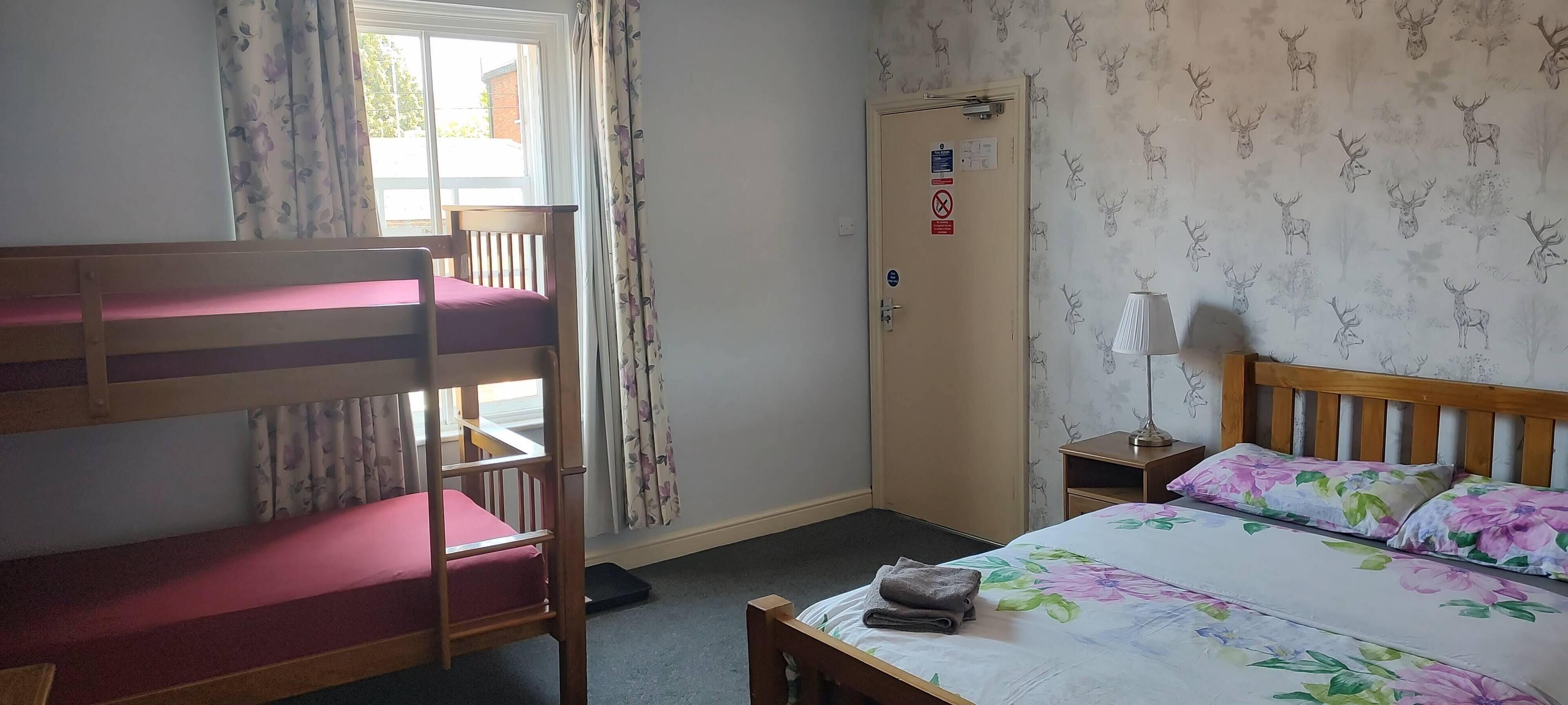 A room with bunk beds, a desk, a lamp, and a door with signs.