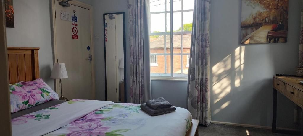 Une chambre à coucher avec un lit, un bureau, une fenêtre avec des rideaux et une porte avec une pancarte.