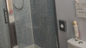 A bathroom with a glass-enclosed shower, a toilet, and a small sink. - Reindeer Accommodation (Southwell)