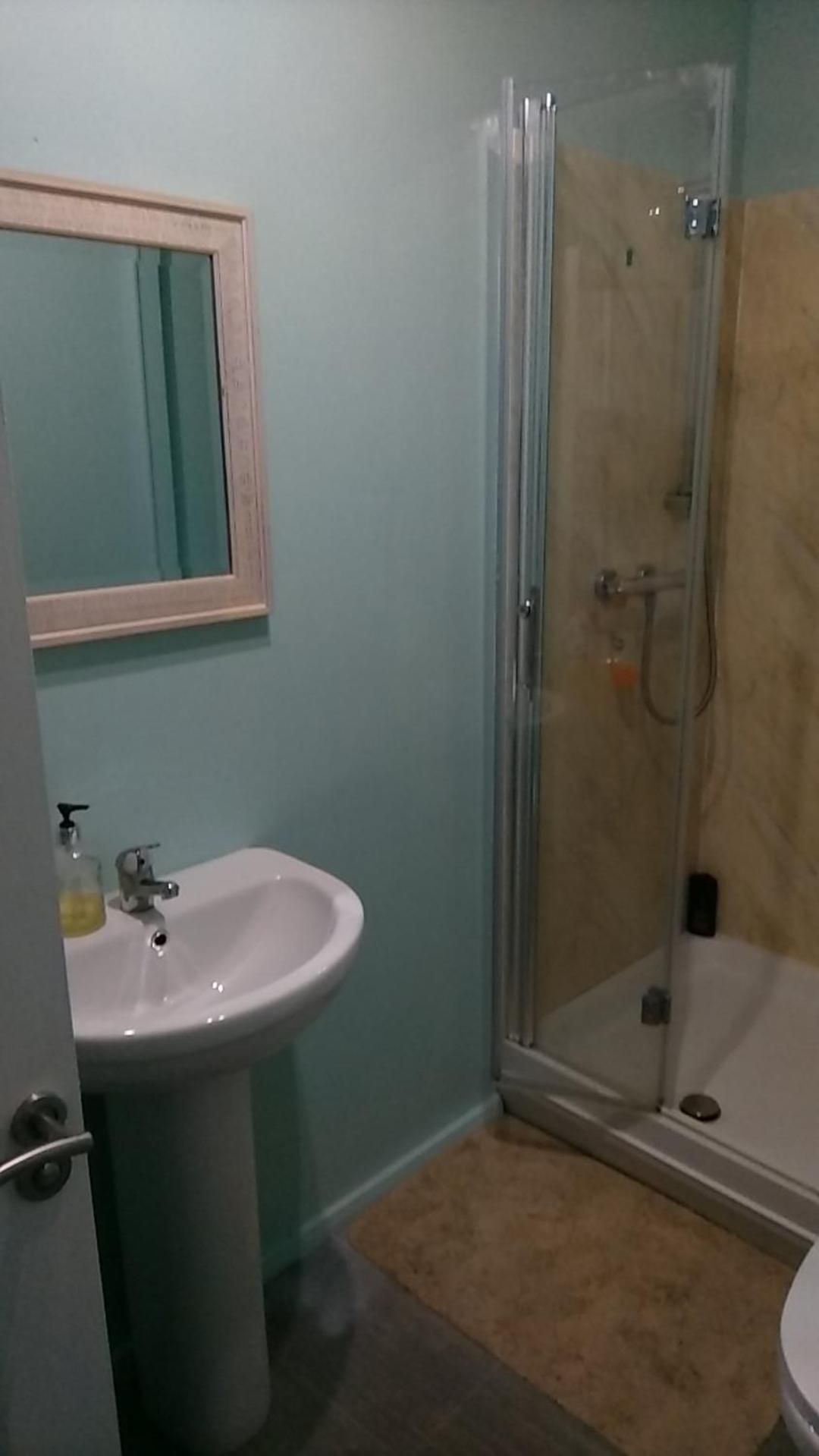 A bathroom with a sink, mirror, and glass-enclosed shower.