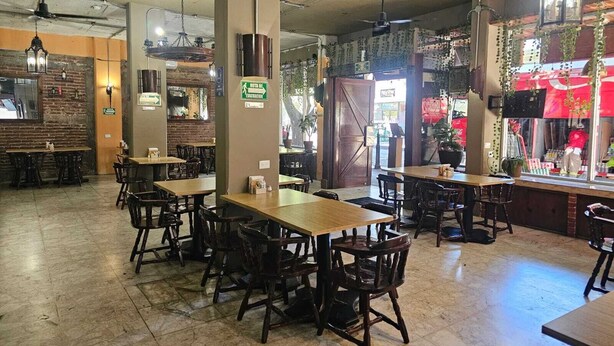 A restaurant with wooden tables and chairs, a brick wall, and hanging plants. - Hotel Plaza Real La Paz (La Paz)