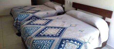 A double bed with a patterned quilt, a wooden headboard, and a bedside table.