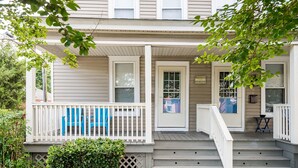 A two-story house with a porch, a welcome sign, and a small table.