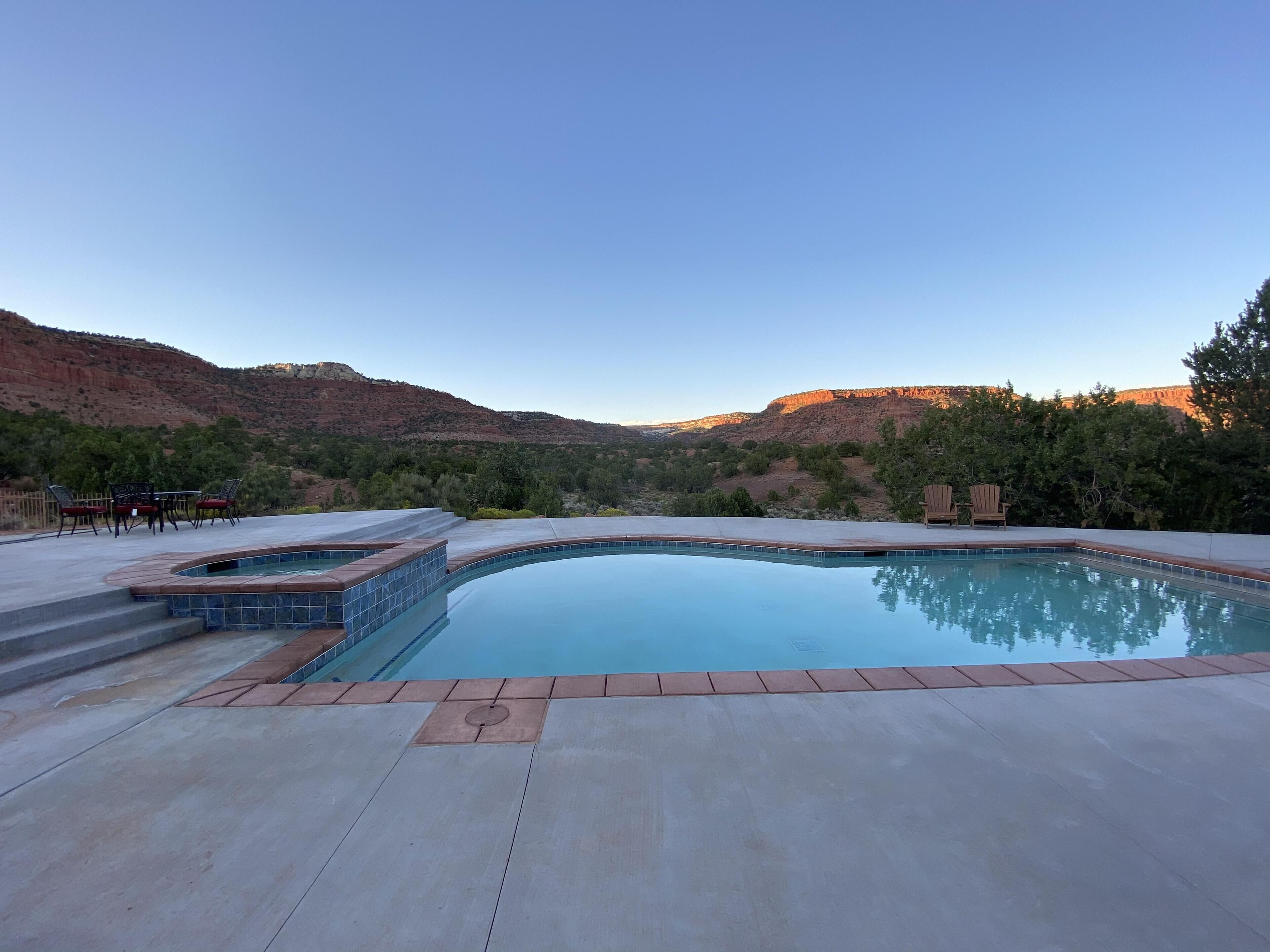 A swimming pool with a view of red rock hills and trees.