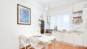 A modern kitchen with white cabinets, a dining table with chairs, and a framed picture on the wall. - GuestHost - The apartment is located on the first floor of a building with a lift, not suitable for the disabled.In 45 square meters of space, it comfortably accommodates 3 people with one bedroom.Located in the Portello district, one of the most histori (Padova)