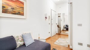 A modern living room with a sofa, a painting, and a hallway leading to another room. - GuestHost - The apartment is located on the first floor of a building with a lift, not suitable for the disabled.In 45 square meters of space, it comfortably accommodates 3 people with one bedroom.Located in the Portello district, one of the most histori (Padova)