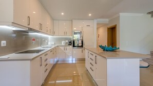 A modern kitchen with white cabinetry, stainless steel appliances, and a central island. - Boavista Resort - Casa Belinda (Lagos)