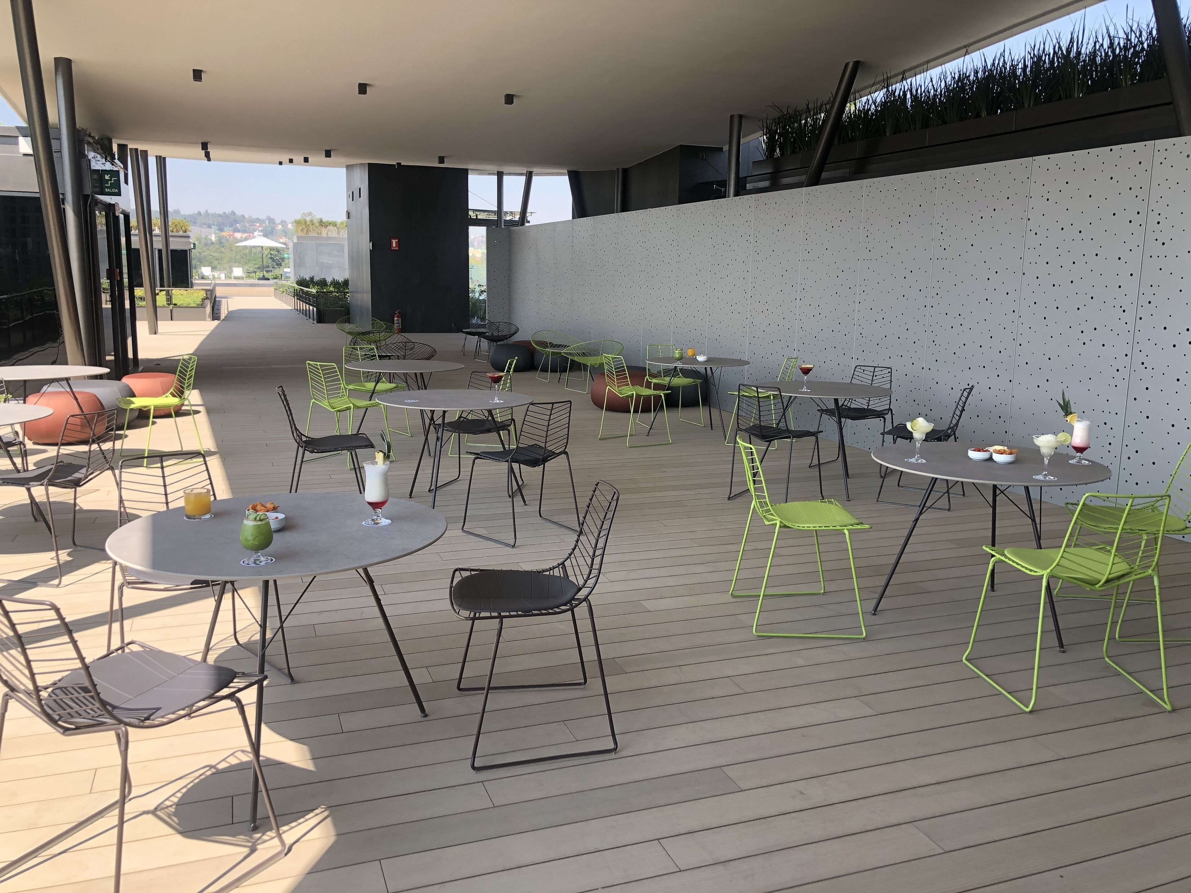 An outdoor patio with round tables and chairs, some with drinks and snacks.