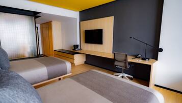 Una habitación de hotel moderna con dos camas, un escritorio, una silla, un televisor y una cafetera.