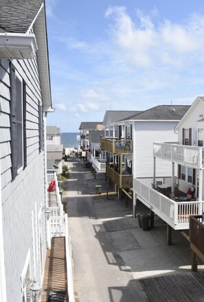 En gata som ligger längs kusten, med fastigheter som vetter mot stranden, inklusive balkonger och utsikt över havet.