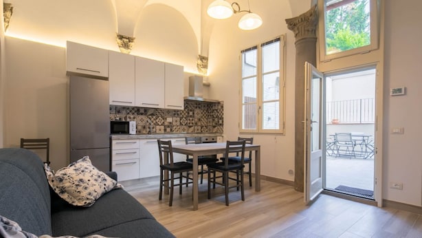 A modern kitchen with white cabinets, a dining table with chairs, and a large window.
