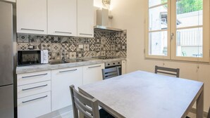 A modern kitchen with white cabinets, a microwave, a stove, and a window with a view of greenery.