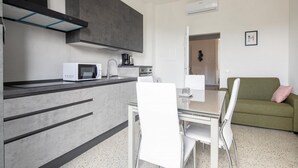 Eine moderne Küche mit Mikrowelle, Kaffeemaschine und einem Essbereich mit Glastisch und Stühlen.