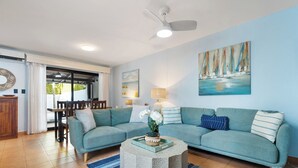 A living room with a light blue sofa, a round coffee table, and a painting of sailboats on the wall. - Spacious Home w/ Private Pool & Covered Patio Near the Beach (Tempate)